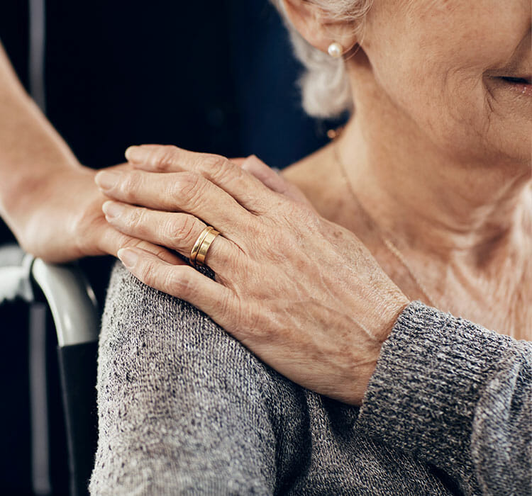 caretaker with hand on senior woman's shoulder